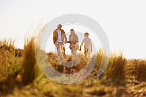 Family, grass and walk at sunset, nature and bonding with exercise for parents and children. Lens flare, autumn and hike