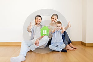 Family with green house showing thumbs up at home