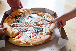 Family group dinner. Hands taking slices of pizza with box. Friends Happiness Enjoying Eating Concept