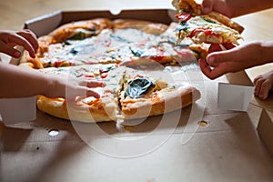 Family group dinner. Hands taking slices of pizza with box. Friends Happiness Enjoying Eating Concept