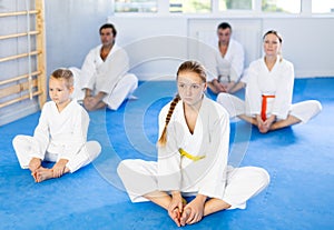 Family during group karate training with trainer in gym performs stretching of muscles by performing butterfly exercise