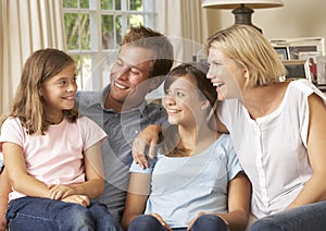 Family Group Sitting On Sofa Indoors