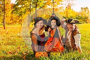 Family in Halloween costumes sitting on the grass