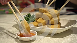 Family hands chopsticks eating fried tofu with salt and pepper vegan healthy food Hong Kong Chinese cuisine