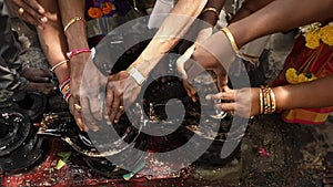 Family hands fixing or establishing shivalinga at temple