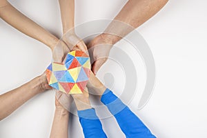 Family hands holding colorful paper heart on white background. World autism awareness day concept