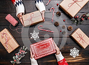 Family Hands showing Christmas present on wooden background