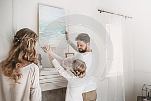 Family hanging picture of sea over the fireplace at home