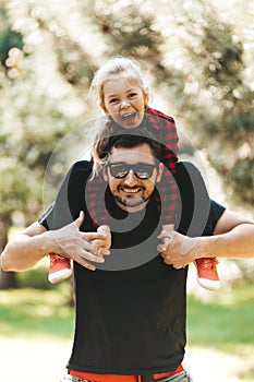 Family happiness. Dad`s daughter is on his shoulders, smiling and fooling around. A fun moment in entertainment