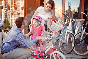 Family with happy kid having fun outdoor shopping new bicycle and helmets