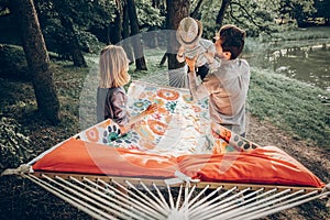 Family happy moments. summer vacation. hipster family playing with cute little son on hammock in summer sunny park. stylish mom