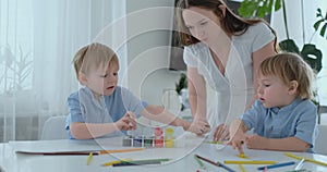 The family has fun painting on paper with their fingers in paint. Mom and two children paint with fingers on paper