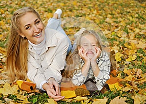 The family has fun in the park. Girl and mother lie on the blanket, young woman looks at the camera and smiles