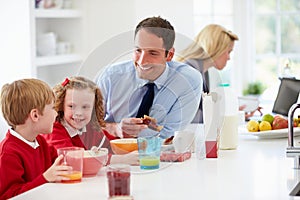 Family Having Breakfast In Kitchen Before School And Work