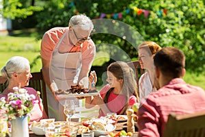 Family having dinner or barbecue at summer garden