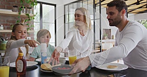 Family having food at dining table in kitchen at comfortable home 4k