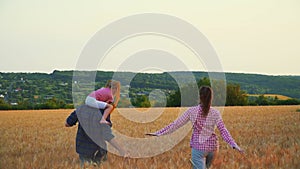 Family having fun in the field at sunset. Summer wheat harvest. Happy family father, mother and child daughter launch a