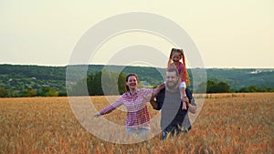 Family having fun in the field at sunset. Summer wheat harvest. Happy family father, mother and child daughter launch a