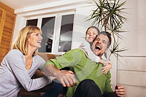 Family having fun on floor of in living room at home, laughing