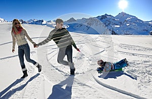 Family having fun on fresh snow at winter vacation