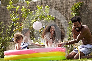 Family Having Fun In Garden Paddling Pool