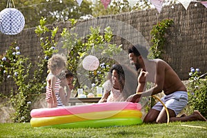 Family Having Fun In Garden Paddling Pool