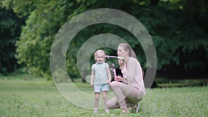 Family Having Fun. Mom And Child Making Soap Bubbles Outdoors