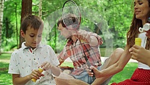 Family having fun in park together. Happy siblings playing with soap bubbles