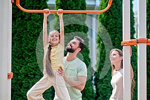 A family having fun at the sports gound on horizontal bar