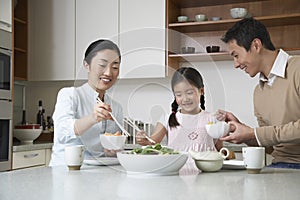 Family Having meal With Chopsticks In Kitchen photo