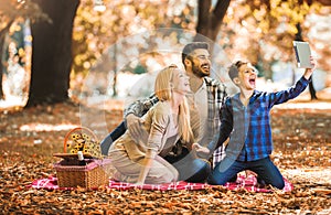 Family having picnic in autumn park, using digital tablet