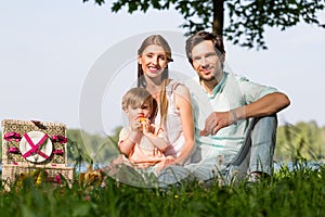 Family having picnic at lake sitting on meadow