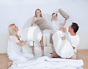 Family Having A Pillow Fight Together On Bed