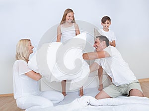 Family Having A Pillow Fight Together On Bed