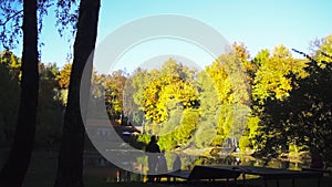 Family having rest near a beautiful pond in the city park in autumn