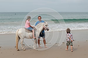 Family having a riding lesson on a beach