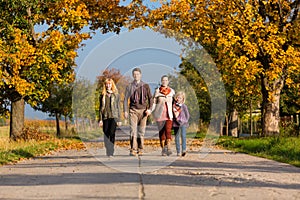 Family having walk in front of colorful trees in autumn