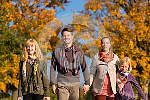 Family having walk in front of colorful trees in autumn