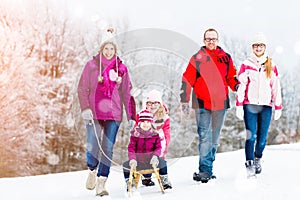 Family having winter walk in snow with sled