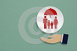 Family ,health or life insurance concept, family under umbrella with businessman hand paper cut on grunge green background