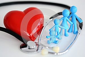 Family healthcare concept with plastic toys, red heart and stethoscope on white background