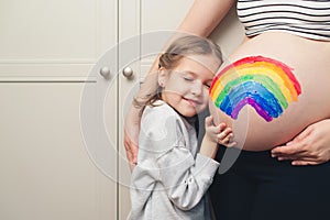 Family, healthy pregnancy and baby birth. Sweet little daughter painting pregnant belly her mother. Baby birth expecting time and