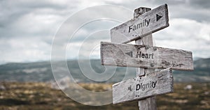 Family heart dignity text engraved on wooden signpost outdoors in nature.
