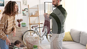 Family, help and parents with laundry to fold and their baby playing in the living room at home. Happy couple doing