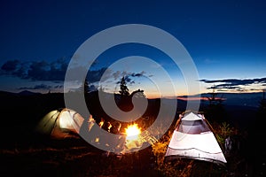 Family hikers having a rest at night camping in mountains