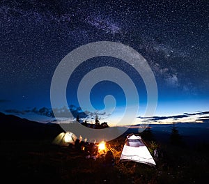 Family hikers having a rest at night camping in mountains