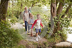 Family Hiking Along Path By River In UK Lake District