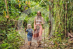 Family in hiking. Mom and son walking in the forest with trekking sticks