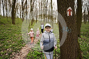 Family hiking together. Boy near trail marker on tree at spring forest