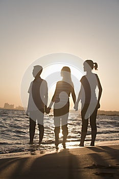 Family holding hands on the beach, sunset